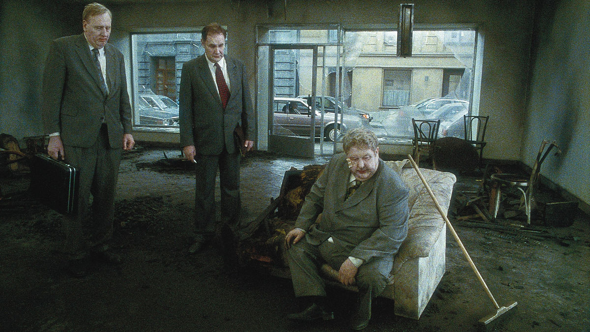 Lars Nordh (seated) in the ruins of his burned business in Songs from the Second Floor (2000)