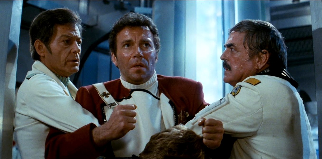 A distraught Captain Kirk (William Shatner) is restrained by Dr McCoy (DeForest Kelley) and Mr Scott (James Doohan) in Star Trek II: The Wrath of Khan (1982)