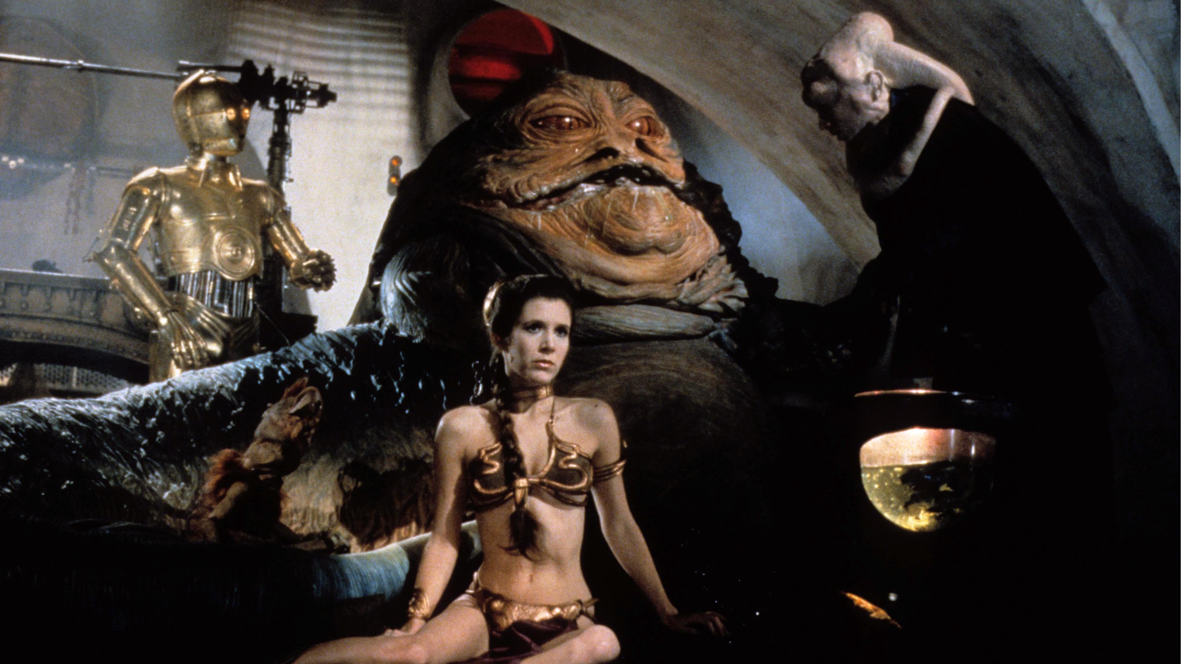 The infamous scene with Princess Leia (Carrie Fisher) as a slave girl to Jabba the Hut with C3P0 in the background (l) in Star Wars Episode VI Return of the Jedi (1983)
