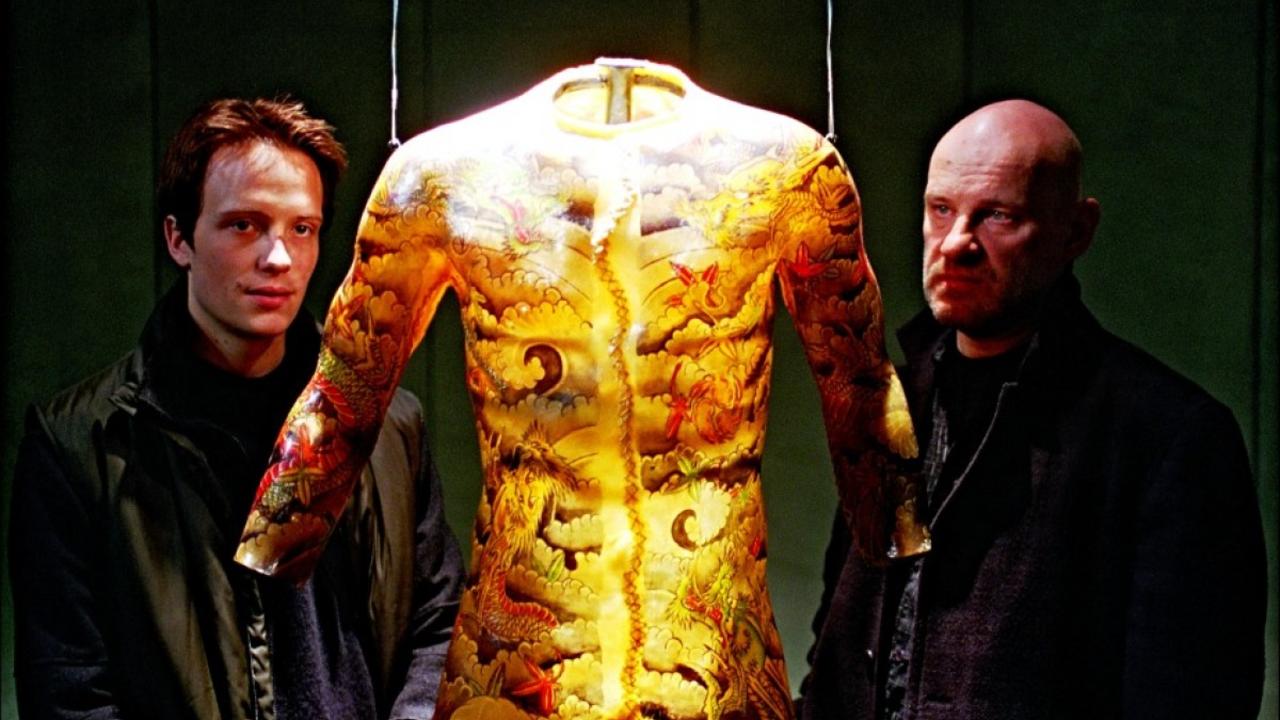 (l to r) August Diehl and Christian Redl view one of the collected tattoos in Tattoo (2002)