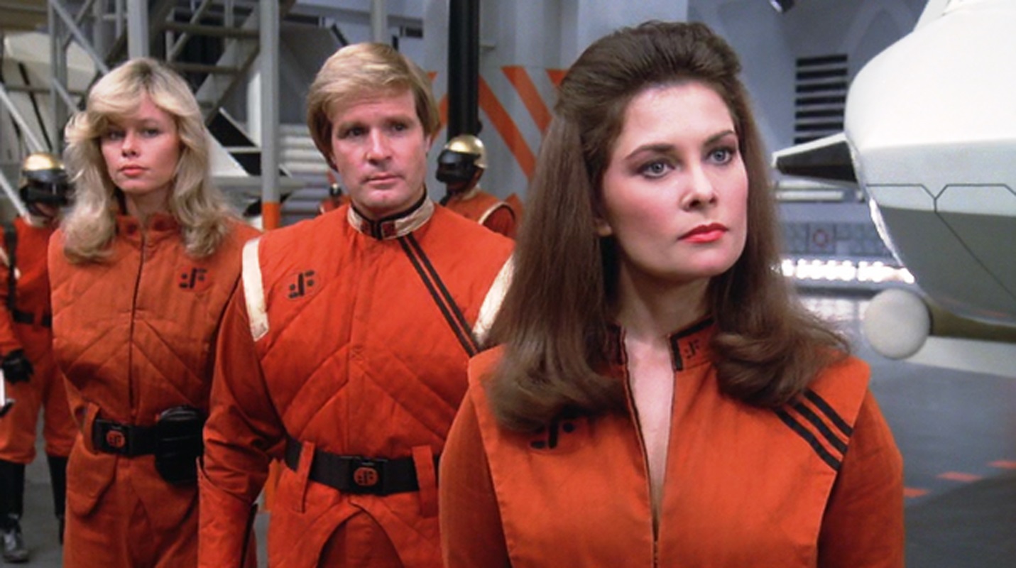 The Visitor leader Diana (Jane Badler) (r) with Martin (Frank Ashmore) behind her in V (1983)