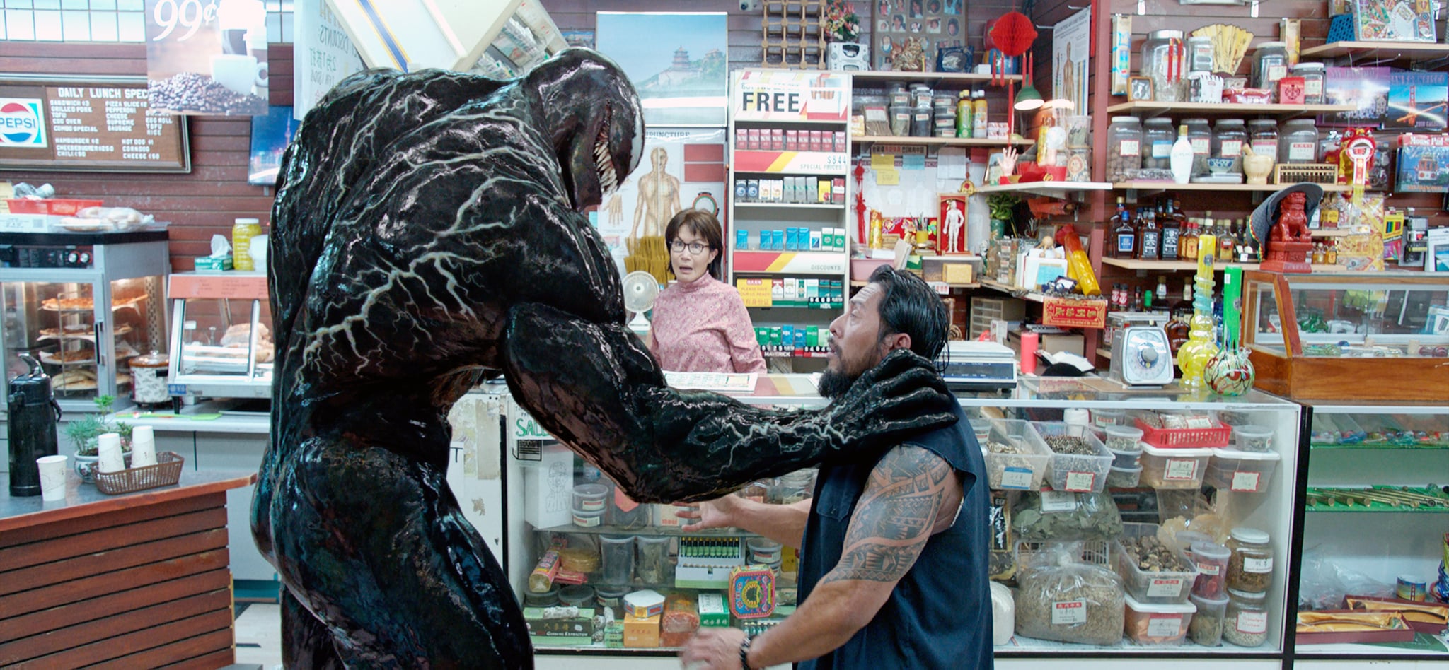 Venom (Tom Hardy) deals with a petty hood while convenience store owner Mrs Chen (Peggy Lu) looks on in Venom (2018)