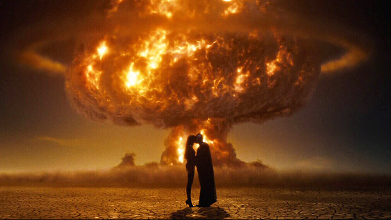 Iconic image of Scarlet Spectre and Nite Owl kissing silhouetted against an atomic bomb in Watchmen (2009)