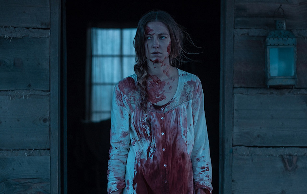 Caitlin Gerard alone in the cabin on the prairies haunted by possibly imagined demons in The Wind (2018)