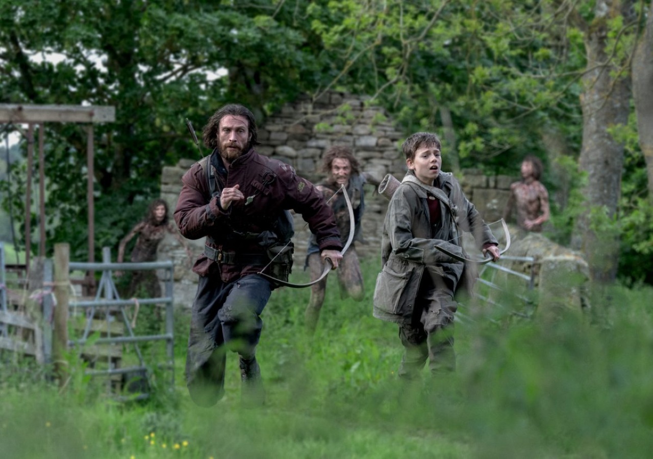 Spike (Alfie Williams) and Aaron Taylor-Johnson flee zombies in 28 Years Later (2025)