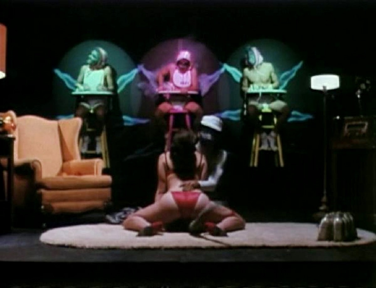 Women performer in front of projected adults dressed as babies in Cafe Flesh (1982)