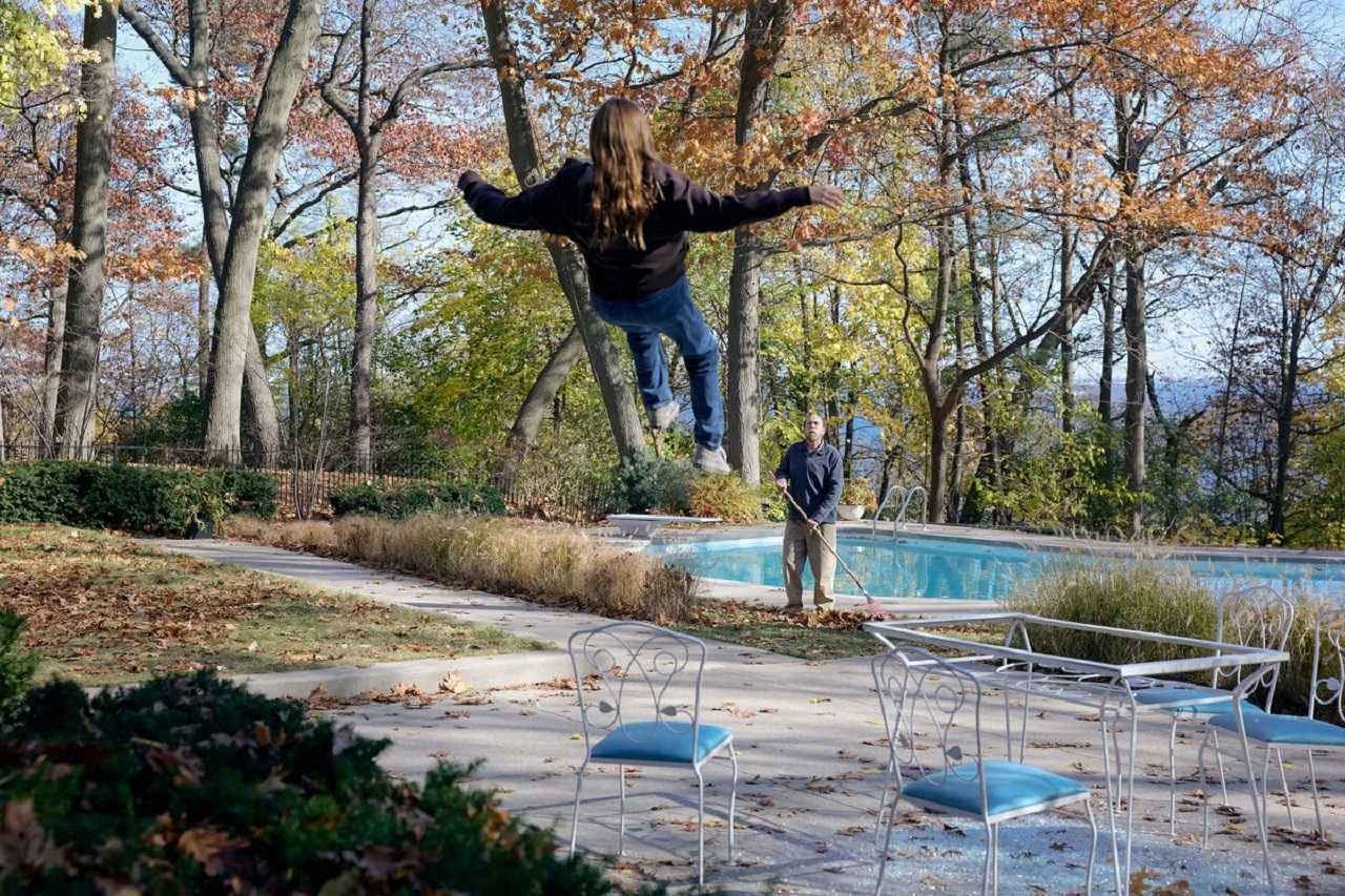 Nicolas Cage rakes leaves as Lily Bird levitates in Dream Scenario (2023)