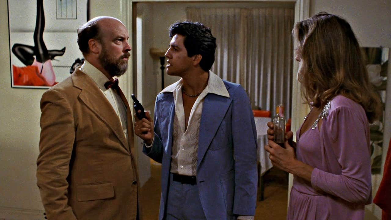 Paul Bland (Paul Bartel) is threatened by Raoul (Robert Beltran) as Mary Bland (Mary Woronov) looks on in Eating Raoul (1982)