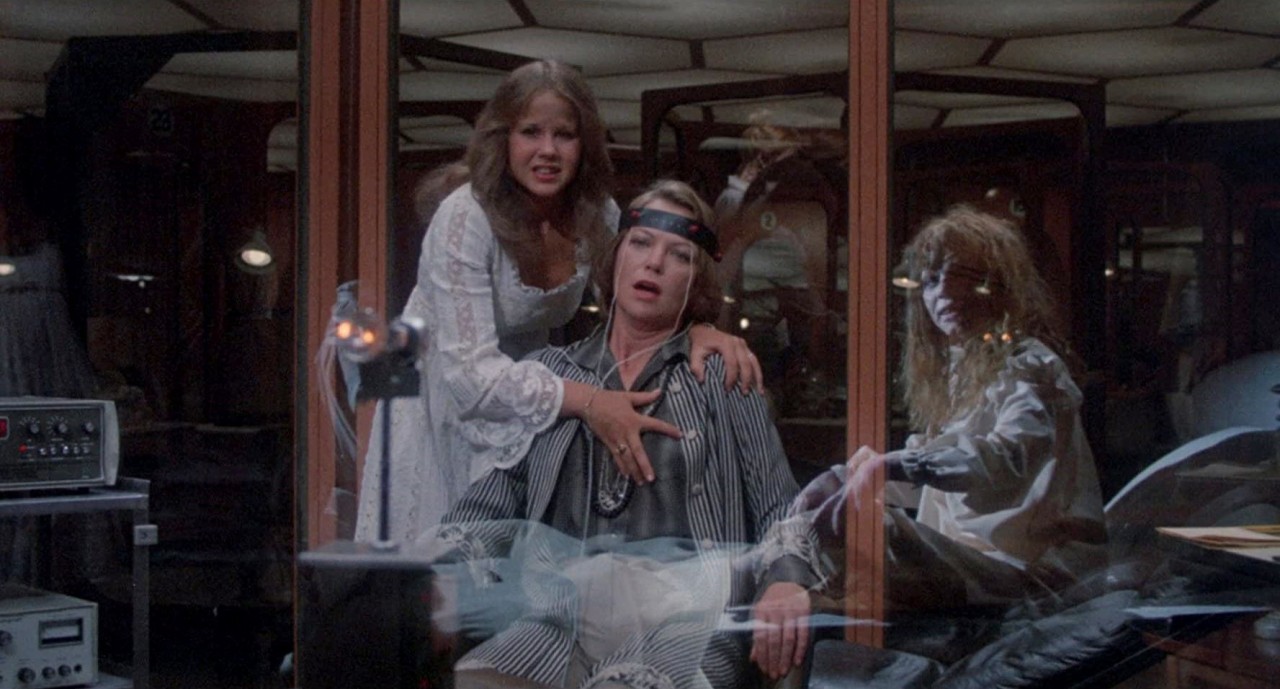 Good and evil Regans (Linda Blair) hover over Dr Gene Tuskin (Louise Fletcher) as she enters The Synchronizer in Exorcist II The Heretic (1977)