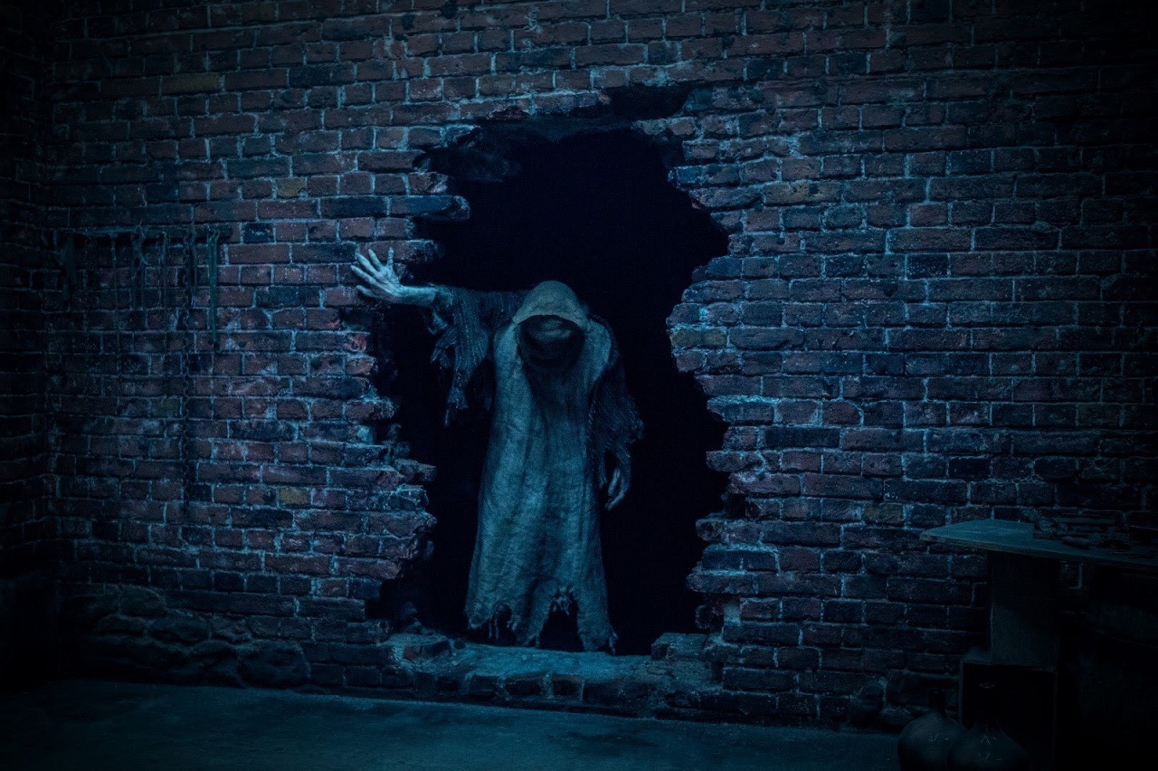The Baghead appears out of the hole in the wall in Baghead (2023)